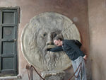 The Mouth of Truth (Bocca della Verita).  It's under the portico of the church of Santa Maria in Cosmedin, across the street from the Temple of Huercules.  It is believed that the huge face was a drain outlet for the Cloaca Maxima, the great sewer built by the Tarquin kinds to drain marshy areas of the city.  It is called the "mouth of truth" because according to medieval legend, anyon putting their hand inside after telling a lie would get bitten.  Monica is still recovering.