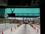Tollgate on the highway to Emei.  We got on the bus without any clear idea of where we would end up.  We had a slip of paper with the name of our intended destination on it, but the ticket agent crossed that name out and wrote something else on our slip.  She then sold us 5 tickets and 50 slips marked "one yuan" for which I paid 50 huan.   After about three hours and one stop we arrived at a bus station.  A mini-bus driver immediately offered to drive us to our starting place for 50 yuan.  I offered her our insurance slips.  She tried to explain to me what the slips were or weren't.  I suspected they weren't another ticket but figured waving them around was helping with the bargaining.  She led me inside the bus station where a big discussion occured between our original driver, some official acting guys, and a policeman or two.  It was pretty clear that everyone was telling the driver that he had somehow goofed and should figure things out.  It turns out we should have gotten out at the first stop.  Eventually, the driver paid the woman from the mini-bus 10 yuan to take us back to the last stop.  The slips turned out to be the "insurance" required of every foreigner who takes a cross-country bus ride.