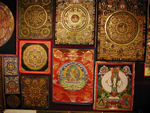 Tanka shop's wares.  A tanka is a Tibetan religious painting or drawing on woven material, usually cotton; it has a bamboo-cane rod pasted on the bottom edge by which it can be rolled up.  Tanka means "something rolled up."  Tankas are meditation aids, though they may be hung in temples or at family altars, carried in religious processions, or used to illustrate sermons. They are not free creations of art, in the Western sense, but are painted according to exact canonical rules. They commonly depict the Buddha, surrounded by deities or lamas and scenes from his life; divinities assembled along the branches of a cosmic tree; the wheel of life; the symbolic visions thought to occur during the intermediate state between death and rebirth; mandalas, symbolic representations of the universe; horoscopes; and Dalai and Panchen lamas, saints, and great teachers.