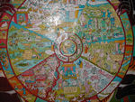 Wheel of life.  In the centere of the wheel are the three basic evils, symbolized by a dove (passion), a green snake (anger), and a pig (ignorance). The intermediate space between the centre and the rim is divided by spokes into five sections, depicting the possible states into which a person can be reborn.  It's supposed to be the realms of gods, people, animals, ghosts, and demons, but we had trouble finding them. Around the rim of the wheel the 12 nidanas, or interrelated phases in the cycle of existence --ignorance, karman formations, rebirth consciousness, mind and body, sense organs, contact, sensation, craving, grasping, becoming, birth, and old age and death.